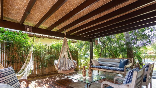 A covered outdoor seating area with a hammock, cushioned seating, and a glass table. - Bz37 House with Pool 200M from the beach! (Armação dos Búzios)