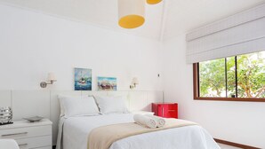 A modern bedroom with a bed, bedside tables, artwork, and a window with a view of trees. - Bz37 House with Pool 200M from the beach! (Armação dos Búzios)