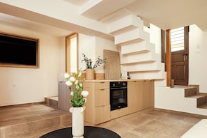 A modern kitchen with a built-in oven, a wooden island, and a vase with flowers on a round table.