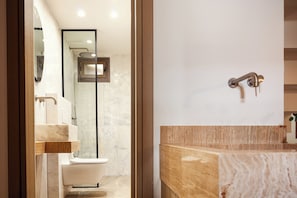 A modern bathroom with a marble sink, a toilet, and a shower area.