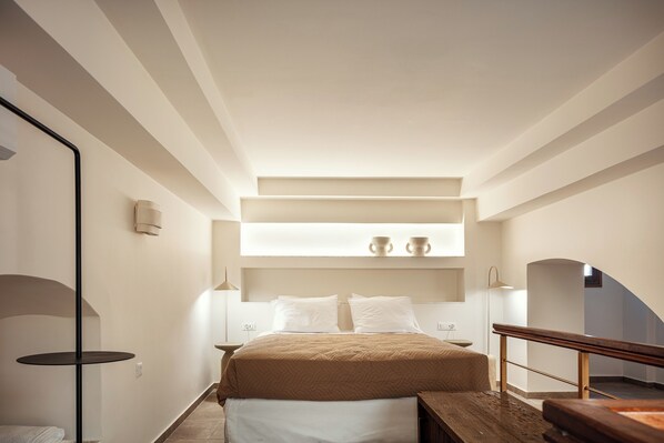 A modern bedroom with a bed, bedside tables, a bench, and a small table with cups. - Sea Path VII old town luxury  80 qm 2 Level House a few steps from the beach (Rethymno)