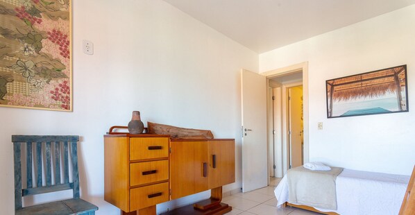 A room with a wooden cabinet, a bench, a bed, and two doors leading to other areas. - Bz43 Feet in the sand! Home with safety and comfort (Armação dos Búzios)