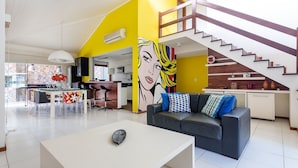 Una sala de estar moderna con un sofá, una mesa de centro y un mural llamativo.