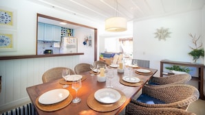 A dining area with a wooden table set for six, surrounded by wicker chairs. - Bz92 Beautiful house 600m from Rua das Pedras! 4 suites (Armação dos Búzios)