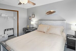 Une chambre à coucher bien rangée, avec un lit, des tables de chevet, un bureau et une chaise.