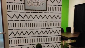 Une pièce avec un mur orné d’un motif, un tableau encadré, une petite table sur laquelle est posée une plante en pot, et un mur d’accent de couleur verte.