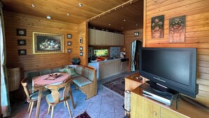 Un intérieur en bois comprenant un coin repas, un canapé, une télévision, une cuisine et des tableaux encadrés.