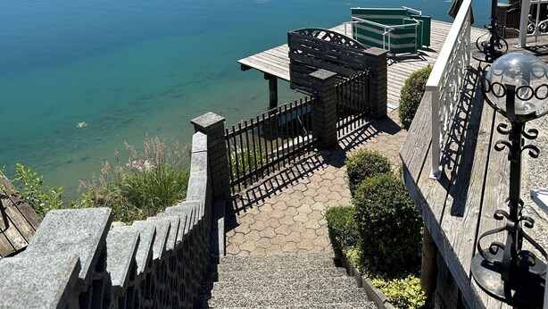 Une vue sur le lac, avec une terrasse en bois, un belvédère et un mur de pierres.