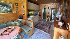 L’intérieur chaleureux d’un chalet avec un plafond en bois, un coin repas comprenant une table et des chaises, une cuisine équipée de placards et d’un évier, et un salon avec un canapé et un tapis.