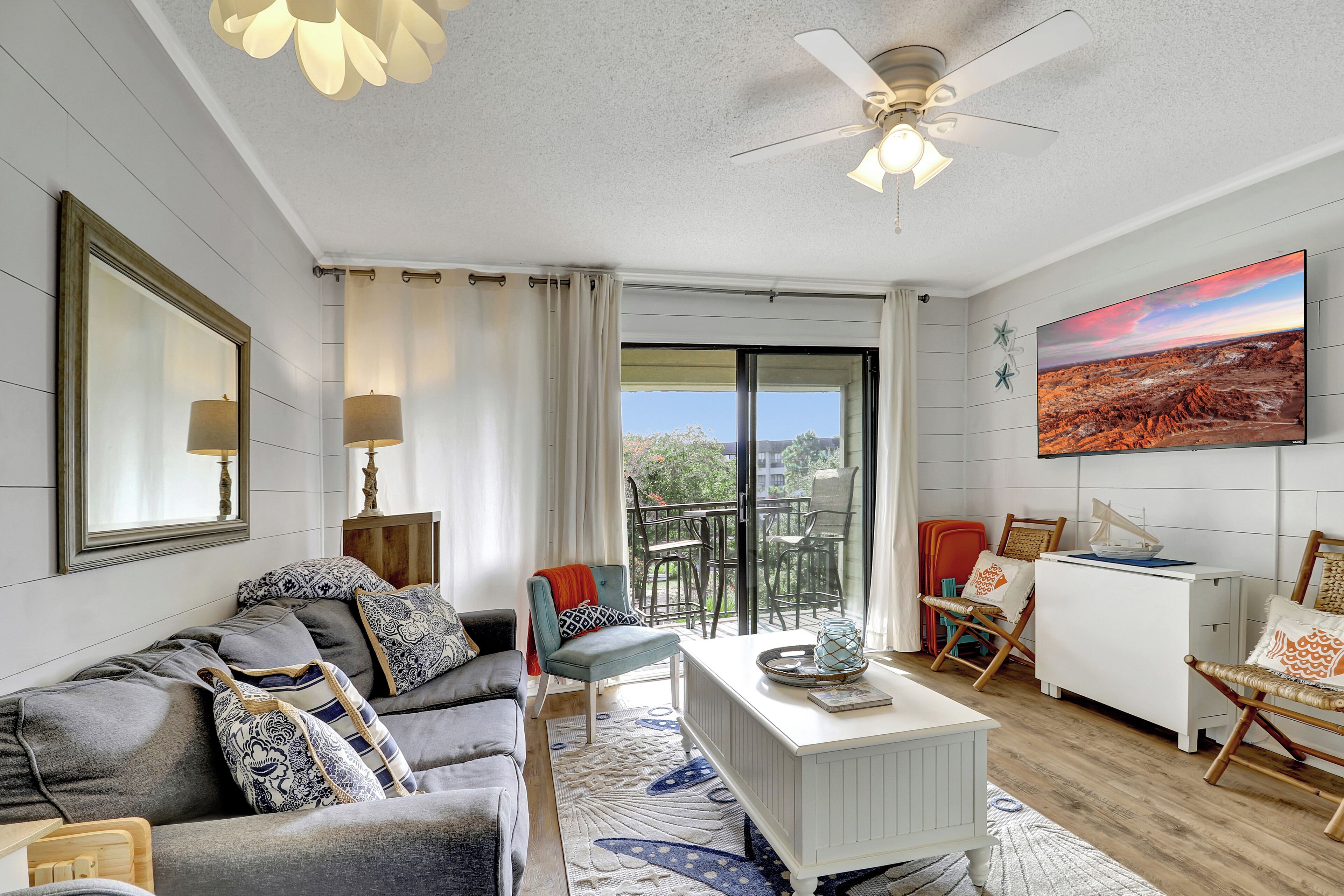 A modern living room with a grey sofa, a white coffee table, and a ceiling fan.