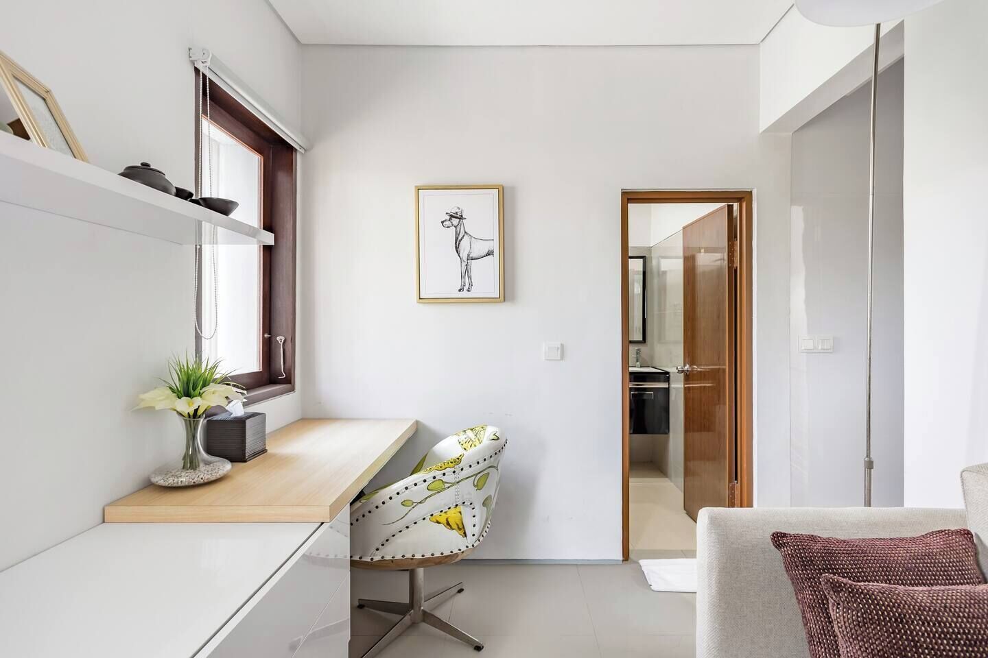 Habitació senzilla amb escriptori, cadira i un quadre al mur.