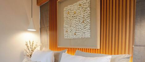 A modern bedroom with a bed, pillows, a bedside table, and a wall-mounted artwork.