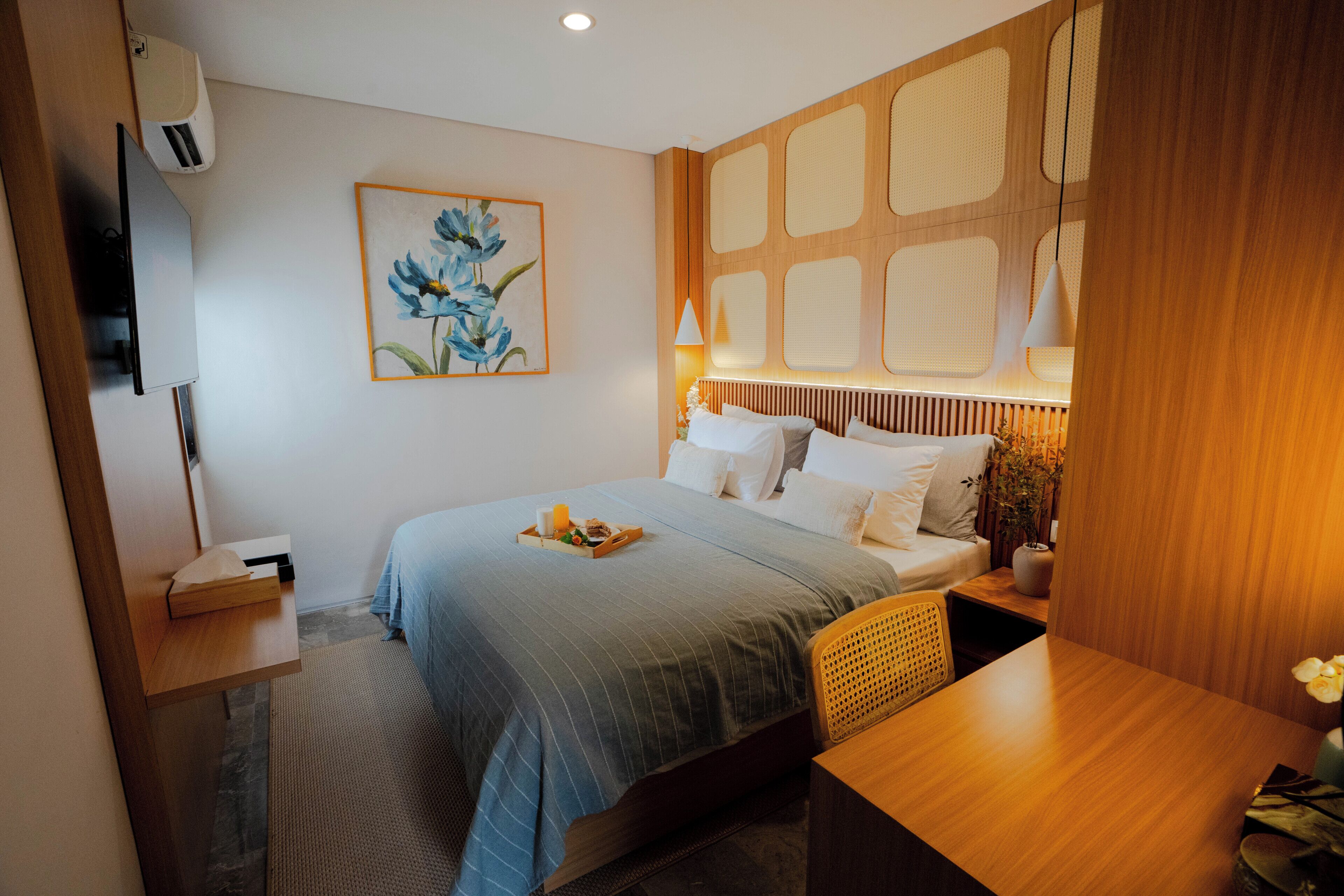 Una habitación de hotel moderna con cama, mesita de noche, lámpara y obras de arte.