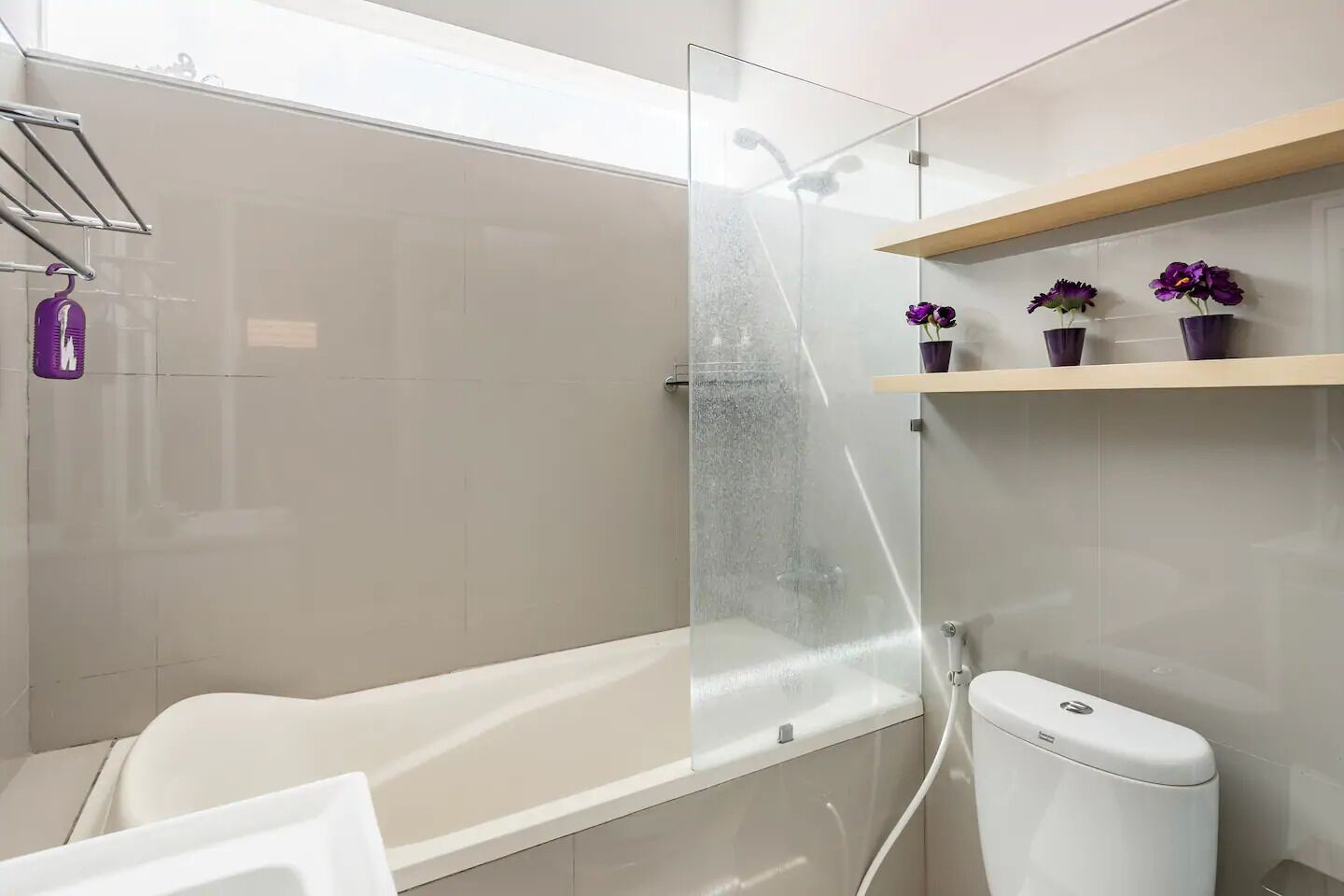 A modern bathroom with a glass-enclosed shower, a white bathtub, and a toilet.