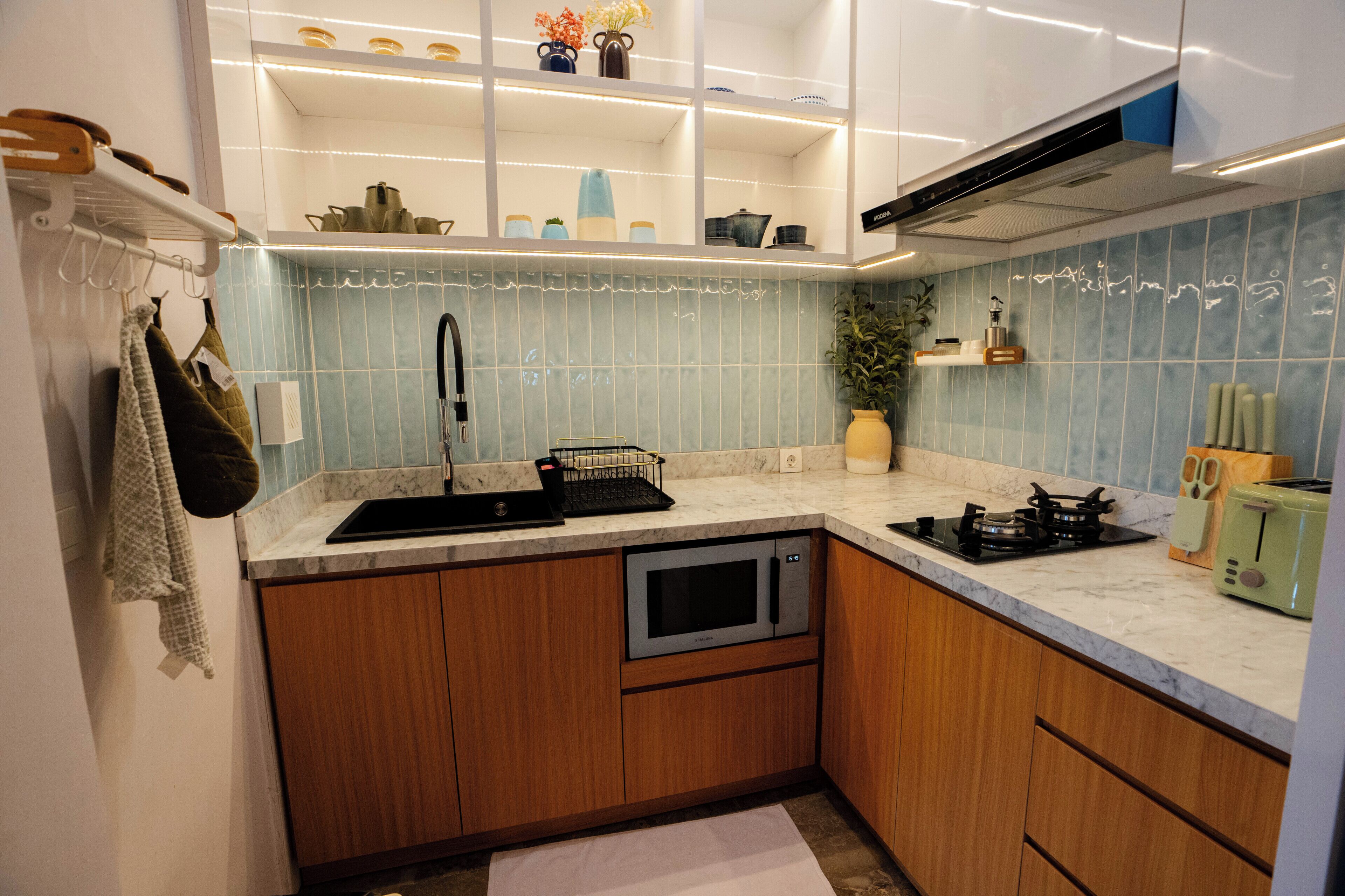 A compact kitchen with a sink, stove, microwave, and a small countertop area.