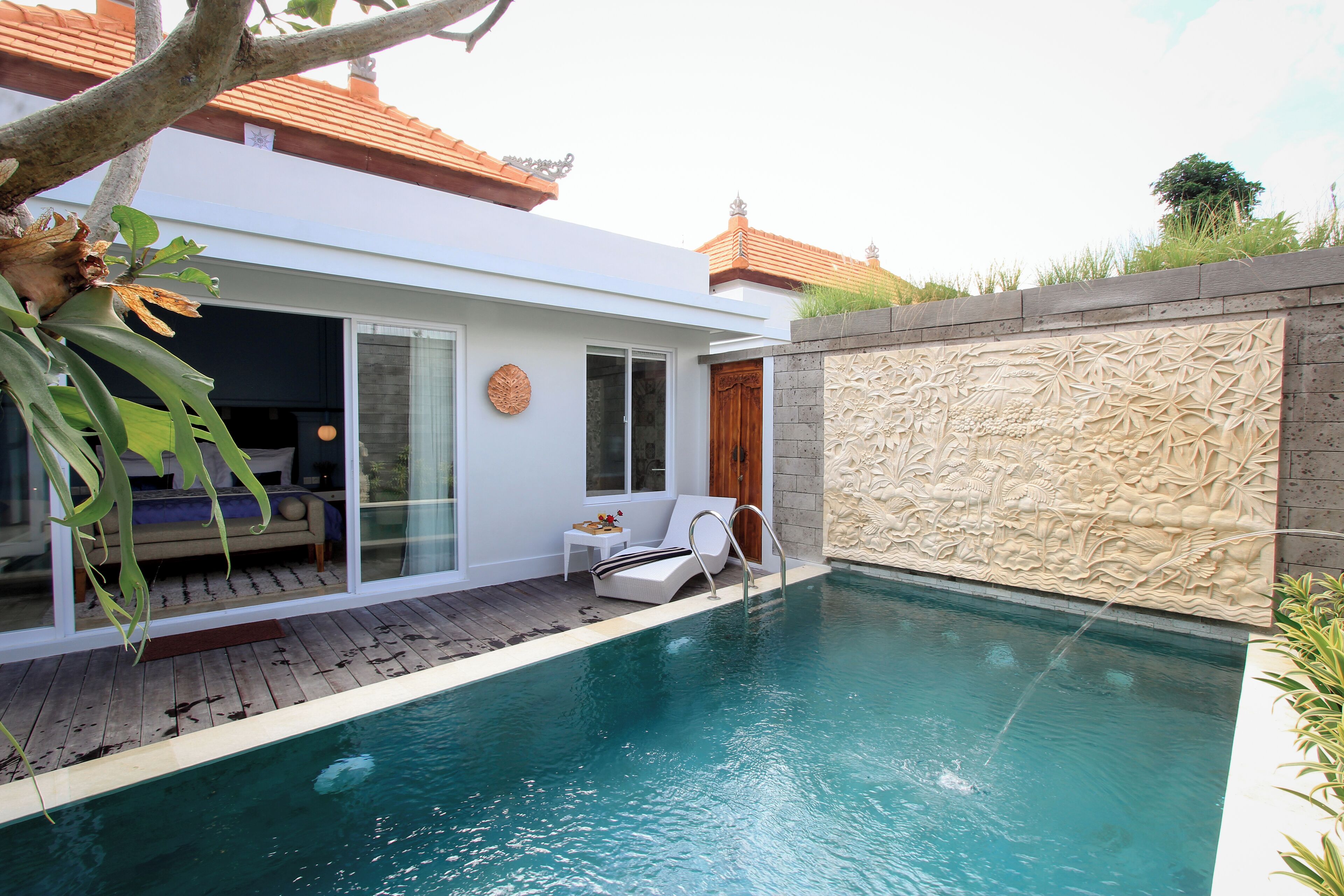 A modern house with a swimming pool, a wooden deck, and a stone wall.