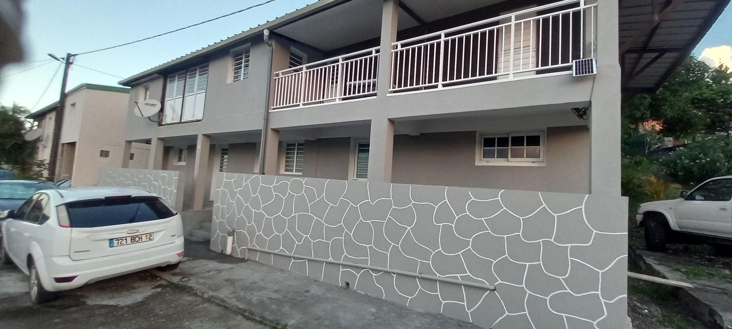 A two-story building with a balcony on the upper floor and a textured wall.