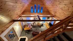 A wooden interior with a dining area, sofa, and staircase. - Cozy 1-bedroom cabin with AC, WiFi & garage in charming Ironwood (Ironwood)