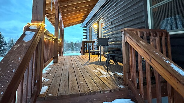 A wooden deck with a railing, a bench, and a table. - Cozy 1-bedroom cabin with AC, WiFi & garage in charming Ironwood (Ironwood)