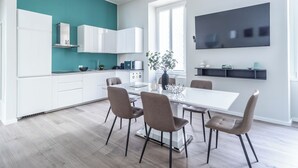 Eine moderne Küche mit weißen Schränken, einer Wand in Türkis und einem Essbereich mit einem weißen Tisch und vier Stühlen.