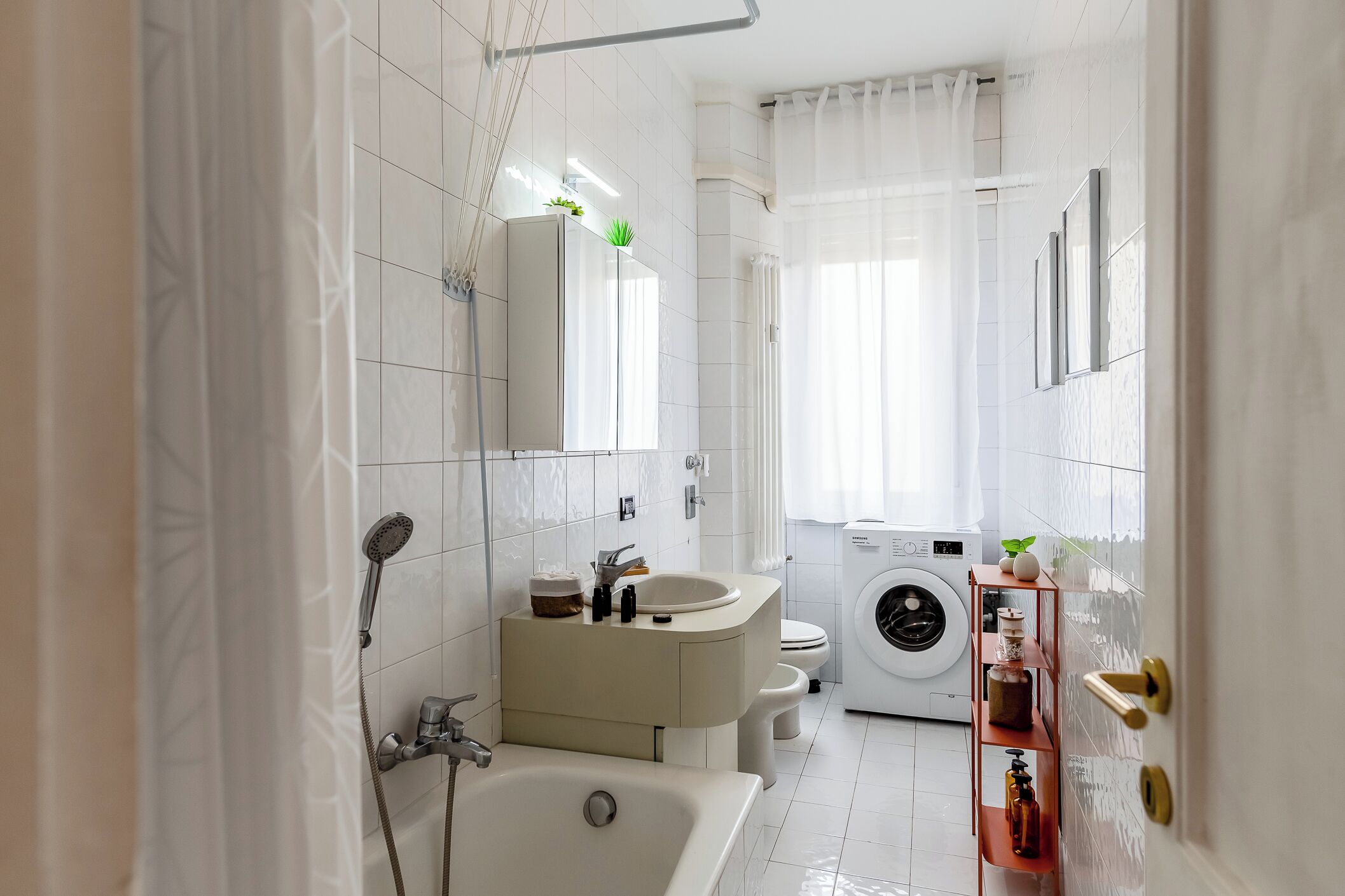 A modern bathroom with a bathtub, sink, toilet, and washing machine.