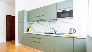 A modern kitchen with green cabinets, a stainless steel sink, and a microwave above it.