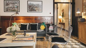 A cozy living room with a wooden headboard, a sofa, a coffee table, and two metal chairs. There are framed pictures on the wall and a lamp on the table. - Joia House is a luxury stately home in Mahon for the best vacation experience (Maó-Mahón)