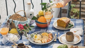 A table set with breakfast items including bread, fruit, and a drink being poured. - Joia House is a luxury stately home in Mahon for the best vacation experience (Maó-Mahón)