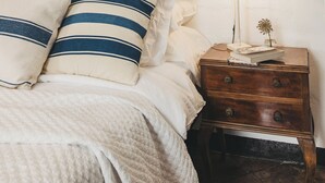 A bedroom with a bed, pillows, a nightstand, a lamp, and a window with a wooden frame. - Joia House is a luxury stately home in Mahon for the best vacation experience (Maó-Mahón)