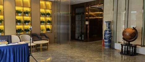 A lobby with a reception desk, seating area, and decorative elements like a globe and vase.