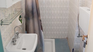 A small bathroom with a toilet, sink, and shower curtain. - Atlantis Rooms (Agios Konstantinos)