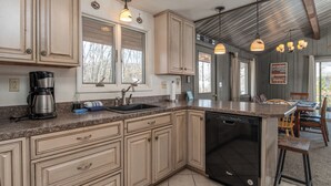 A kitchen with wooden cabinets, a built-in dishwasher, a coffee maker, and pendant lighting.
