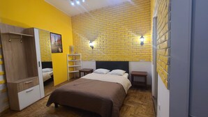 A bedroom with a brick-patterned wall, a bed with a brown bedspread, a wardrobe, and a nightstand with a lamp. - Double apartment, Krakow Old Town (Kraków)