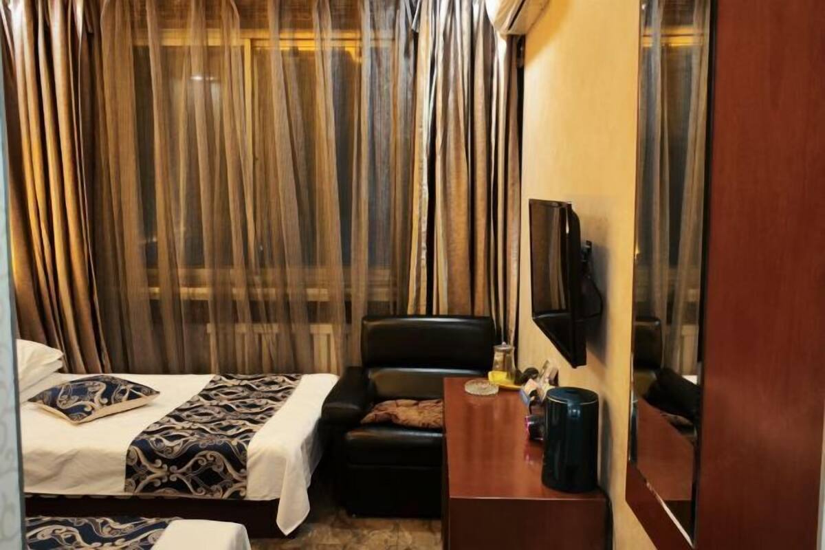 Una habitación de hotel con una cama, un escritorio, una silla y un televisor montado en la pared.