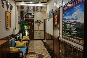 Un vestíbulo de hotel con mostrador de recepción, zona de estar y una pared con un cartel.