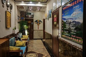 Un vestíbulo de hotel con mostrador de recepción, zona de estar y una pared con un cartel.