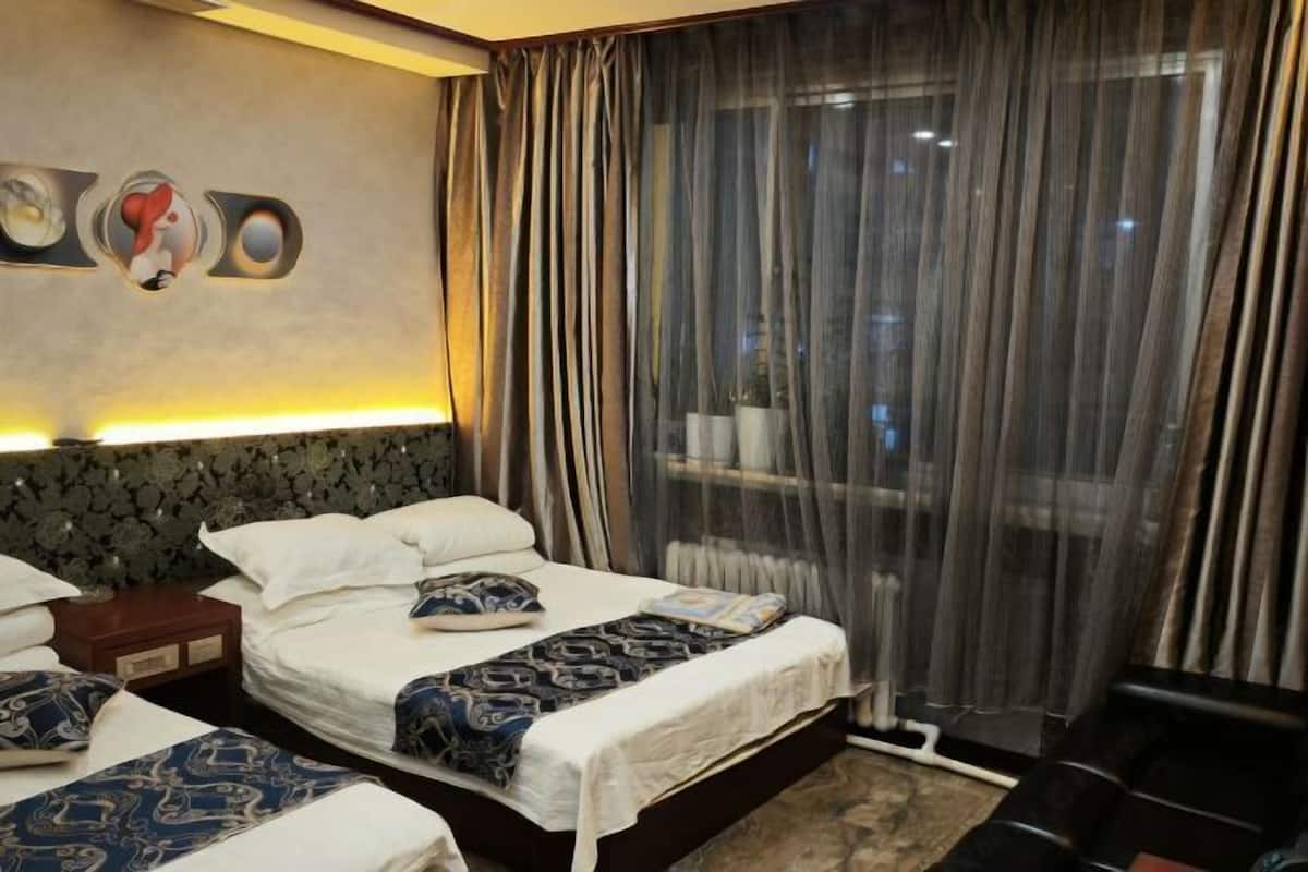 Una habitación de hotel con una cama grande, una mesita de noche y una ventana con cortinas.