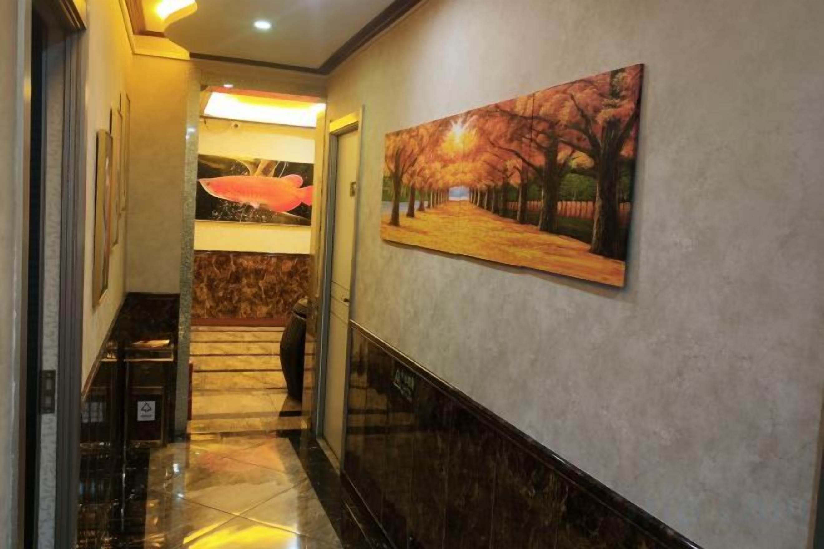 A hallway with a painting of a tree-lined path, a marble floor, and a door leading to another room.