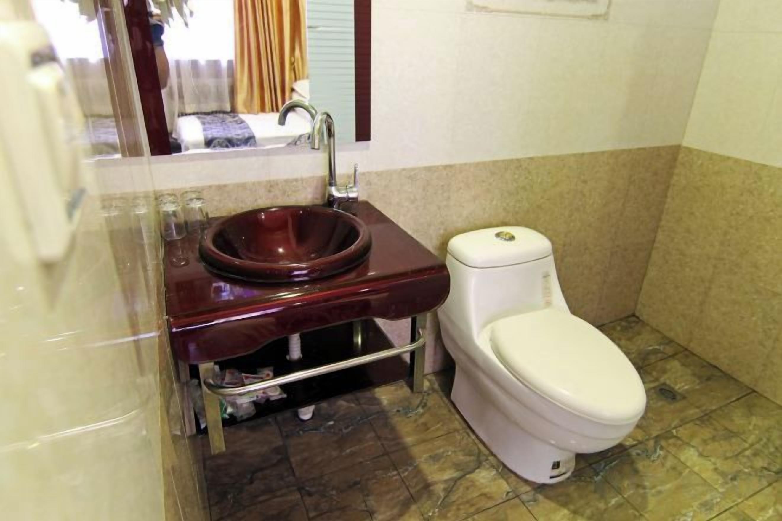 A bathroom with a marble sink, a toilet, and a mirror.