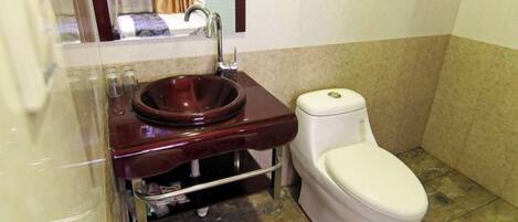 A bathroom with a marble sink, a toilet, and a mirror.
