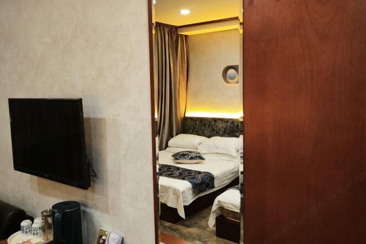 A hotel room with a bed, a television, a coffee maker, and a small table with a tray of items.