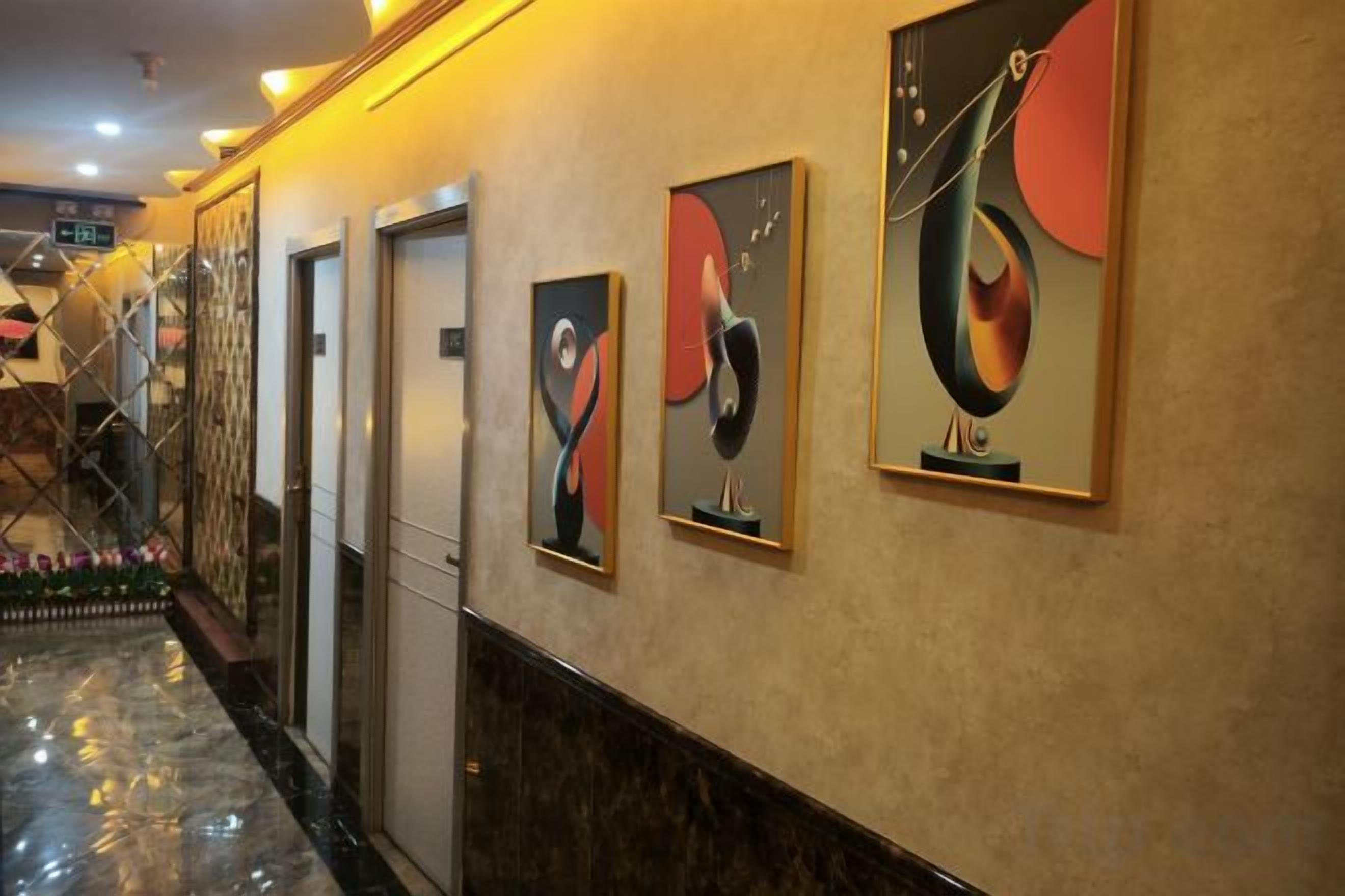 A hallway with artwork on the walls, a marble floor, and a door on the left.