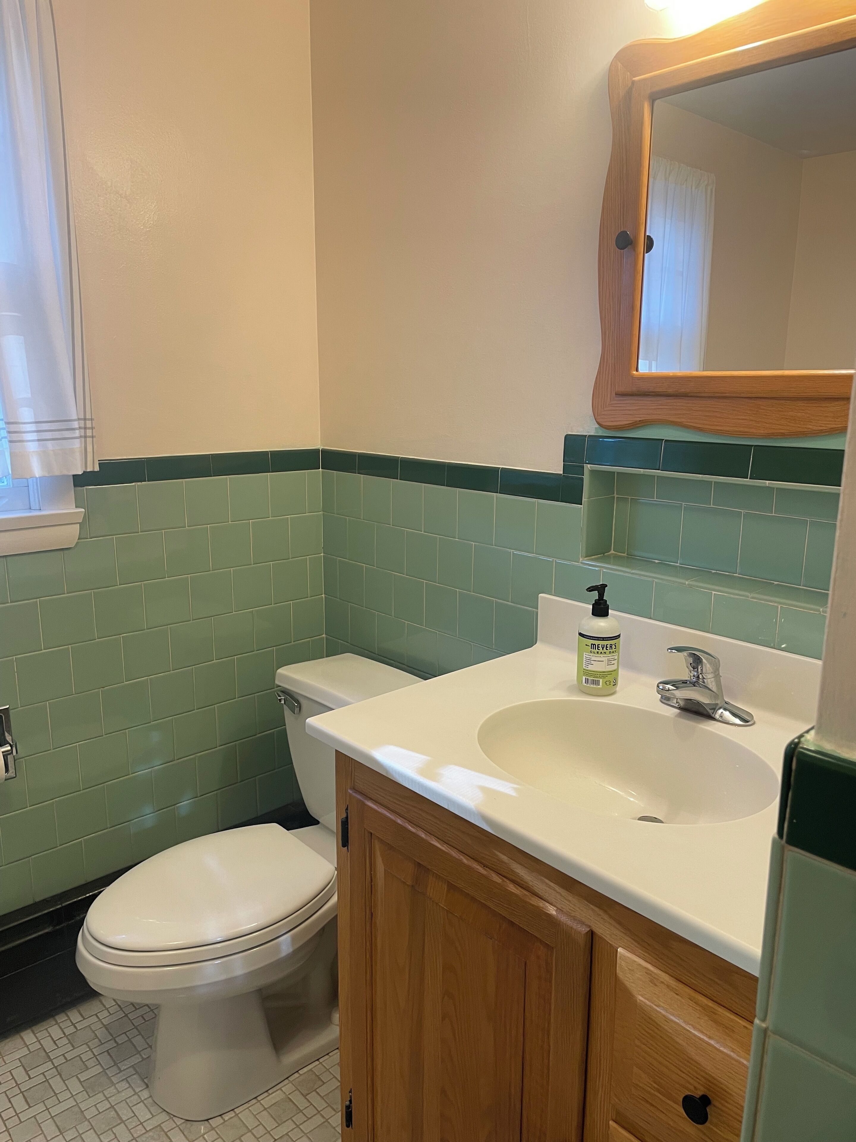 A bathroom with a toilet, sink, and mirror.