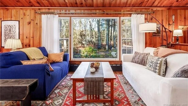 A cozy cabin interior with a blue sofa, a white sofa, and a small table with a woven table runner.