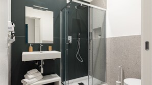 A modern bathroom with a glass-enclosed shower, a white sink, and a toilet. - Nimar suite (Formia)