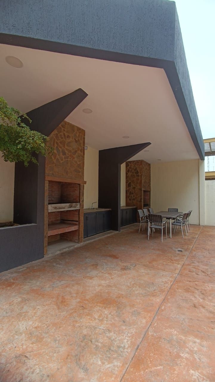 An outdoor patio area with a stone floor, a dining table with chairs, and a built-in grill.