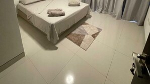 A bedroom with a bed, curtains, and a tiled floor.