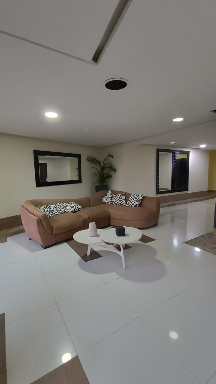 A modern living room with a brown sectional sofa, a white coffee table, and two wall-mounted mirrors.