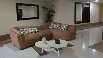 A modern living room with a brown sectional sofa, a white coffee table, and two wall-mounted mirrors.