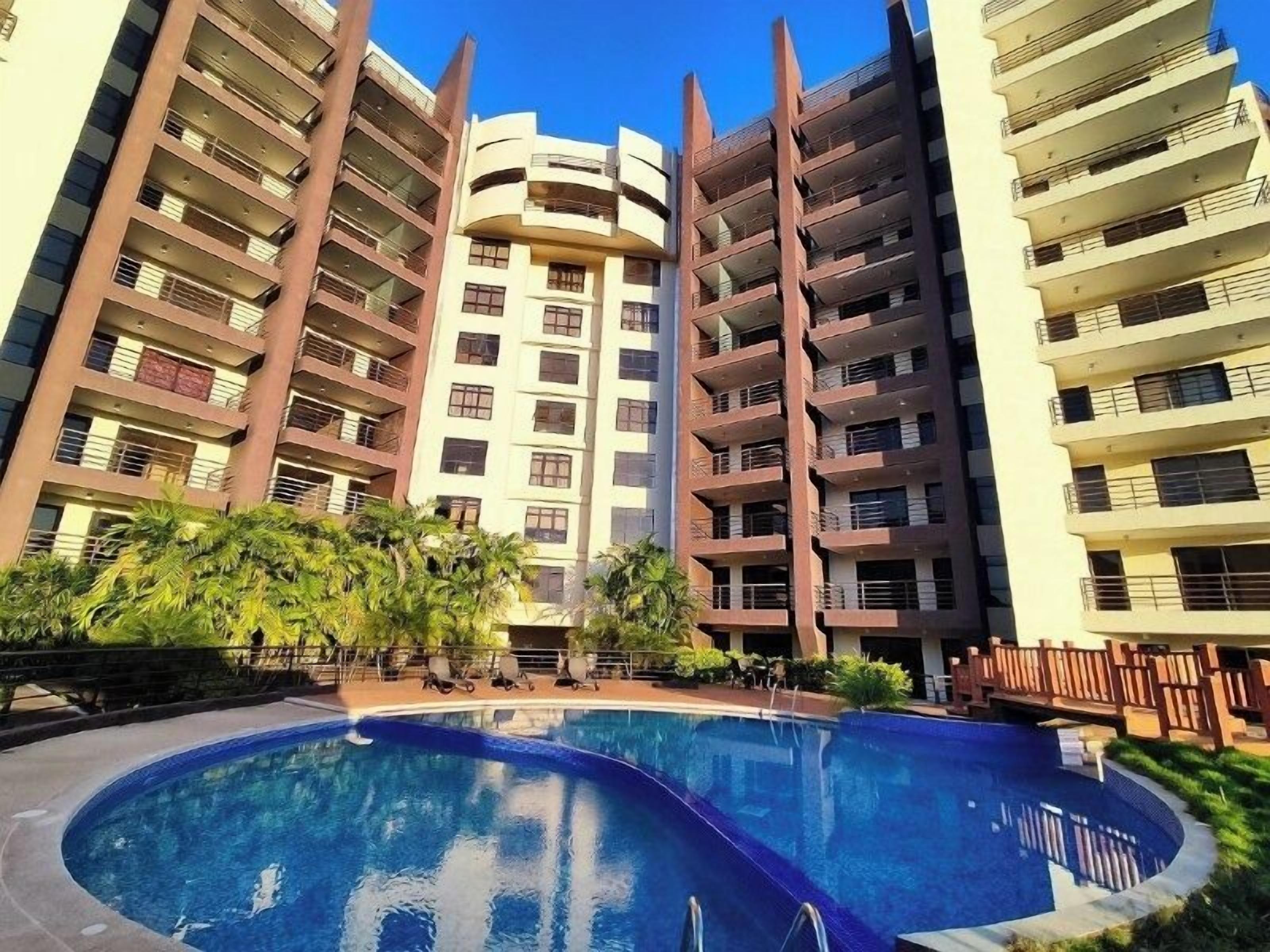 A multi-story residential building with a swimming pool in the foreground.